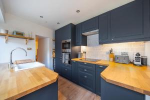 a kitchen with navy blue cabinets and a sink at Charming Cornish Cottage in the heart of St Agnes in St. Agnes 