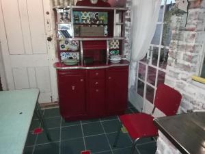 a kitchen with a red cabinet and two red chairs at Koringberg siding cottage in Koringberg +30 photos