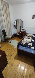 Schlafzimmer mit einem Bett, einem Spiegel und Holzböden in der Unterkunft Etno smeštaj Stojadinović in Svrljig