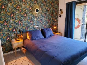 a bedroom with a blue bed with a floral wall at Les goélands in Perros-Guirec