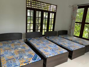 twee bedden in een kamer met ramen bij Nature homes in Moratuwa