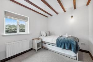 a white bedroom with a bed and a window at 1 The Barn - Brassington in Brassington