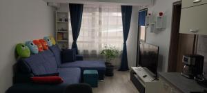 ein Wohnzimmer mit einem blauen Sofa und einem Fenster in der Unterkunft LittleBIG Apartment in Bukarest