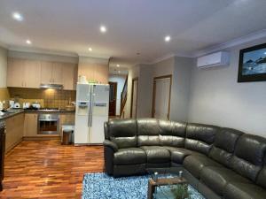 a living room with a leather couch and a kitchen at Townhouse in Mill Park