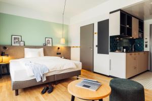 Un dormitorio con una cama y una mesa con un ordenador portátil. en harry's home hotel & apartmens, en Lienz