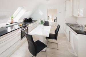 a kitchen with a white table and black chairs at Aurora in Norderney