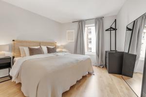 a white bedroom with a large bed and two windows at Flott leilighet i hjerte av Oslo in Oslo