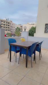 y balcón con mesa de madera y sillas azules. en ArwaHotel Apartments اروى للشقق الفندقية en Áqaba