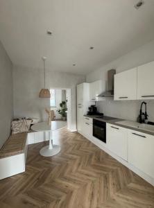 uma cozinha com armários brancos e piso em madeira em La Casa Avenida em Malmedy