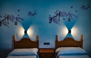 バサにあるHOSTAL CACHEの青い壁と2つの照明が備わるベッドルームのベッド2台