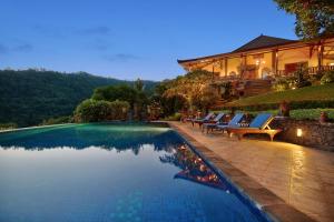 a swimming pool with lounge chairs next to a house at Villa Patria in Lovina