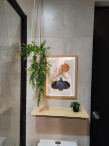ein Badezimmer mit einem Bild und einer Pflanze auf einem Regal in der Unterkunft Eclectic Haven at Bamboo Bay Cebu in Mandaue City