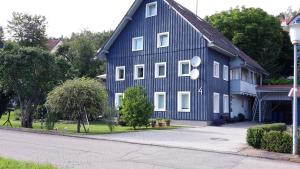 ein blaues Haus mit weißen Fenstern auf einer Straße in der Unterkunft Eschachblick in Zimmern ob Rottweil