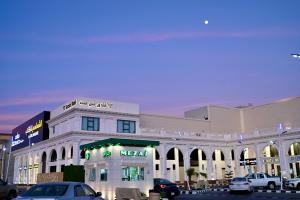 SUN SET HOTEL فندق سن ست في نجران: مبنى ابيض كبير فيه سيارات تقف امامه