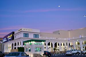 un grand bâtiment blanc avec des voitures garées devant lui dans l'établissement SUN SET HOTEL فندق سن ست, à Najran