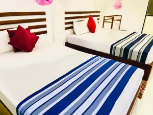 two beds in a room with red and blue pillows at Geethani Tourists Home in Polonnaruwa