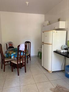 a kitchen with a white refrigerator and a table and chairs at Casa em Ubu in Anchieta