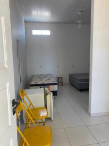 Habitación con 2 camas y silla amarilla en Casa em Ubu, en Anchieta