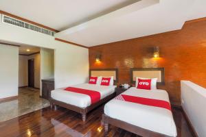 um quarto com 2 camas com almofadas vermelhas e brancas em OYO 920 Saensukkho Hotel And Resorts em Chiang Rai