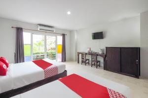 um quarto com uma cama e uma secretária com uma televisão em OYO 920 Saensukkho Hotel And Resorts em Chiang Rai