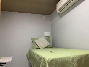 Dormitorio pequeño con cama y aire acondicionado en SUÍTE independente com Ar, Wifi, Smartv e Cozinha en Macaé