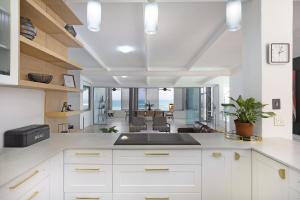 an open kitchen with white cabinets and a dining room at Atlantic Sky Villa in Gordonʼs Bay