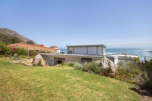 a house on a hill with the ocean in the background at Atlantic Sky Villa in Gordonʼs Bay