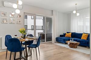 a living room with a blue couch and a table and chairs at Mido Park Apartment with Private Parking & Self Check-in in Bucharest