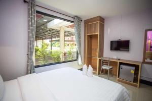 1 dormitorio con cama blanca y ventana en OYO 75464 Nakarin Hotel, en Amnat Charoen
