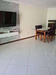 a dining room with a tv and a table and chairs at Praia de Jaúa, Piscina privativa, churrasqueira. in Camaçari