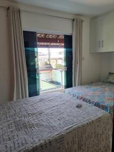 ein Schlafzimmer mit einem Bett und einem großen Fenster in der Unterkunft Praia de Jaúa, Piscina privativa, churrasqueira. in Camaçari