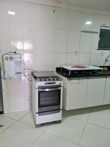 a white kitchen with a stove and a sink at Praia de Jaúa, Piscina privativa, churrasqueira. in Camaçari
