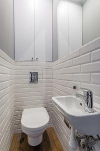 a white bathroom with a toilet and a sink at Chmielna Apartments Warsaw Center in Warsaw