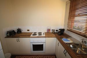 a kitchen with a stove top oven and a sink at Grange Apartments in Bathurst