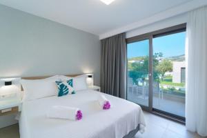 Thassos OLIVIA RESORT في بوتوس: غرفة نوم بسرير ابيض ونافذة كبيرة