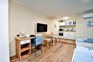 a living room with a desk and a tv and a kitchen at Palmy Apartmanhouse Maglód in Maglód