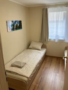 a small bed in a room with a window at Palmy Apartmanhouse Maglód in Maglód