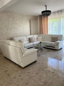 una sala de estar con 2 sofás blancos y una mesa. en Maison de luxe en Saint-Gratien