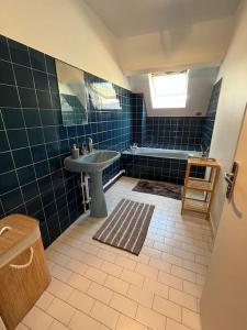 baño de azulejos azules con lavabo y bañera en Maison de luxe en Saint-Gratien