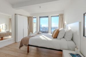ein weißes Schlafzimmer mit einem großen Bett und Fenstern in der Unterkunft Sweet Inn - Stassart in Brüssel