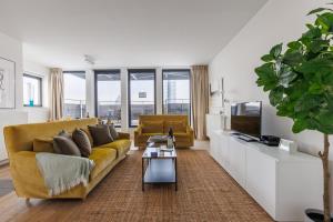 ein Wohnzimmer mit einem gelben Sofa und einem TV in der Unterkunft Sweet Inn - Stassart in Brüssel