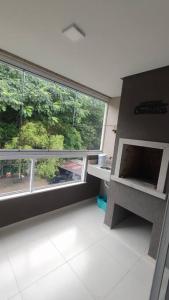 an empty room with a large window and a counter at Apartamento em Bombinhas Próximo ao centro e Passarela do Ribeiro in Bombinhas