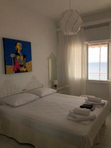 a bedroom with a white bed with a painting on the wall at Cozy Seaview Apartment in Siviri