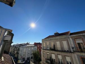 eine Sonne scheint in einem blauen Himmel über Gebäuden in der Unterkunft Low Cost Arroios Rooms in Lissabon