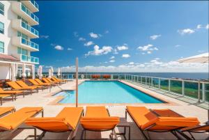a swimming pool with orange chairs and the ocean at Balcony Ocean View ! Pool - WiFi - Gym - Parking in Miami