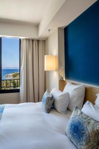 una camera da letto con un grande letto bianco con una grande finestra di Hôtel Helios & SPA - Ile des Embiez a Six-Fours-les-Plages