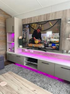 a kitchen with a tv with a man preparing food at Bolton Beer Escape Lodge in Warton