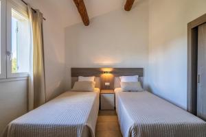 two beds in a small room with a window at Résidence Santa Monica in Bonifacio