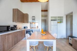 a kitchen with a wooden table and white chairs at Résidence Santa Monica in Bonifacio