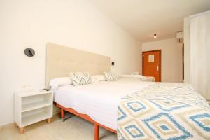 a bedroom with a large white bed and a night stand at Hostal San Juan in El Campello